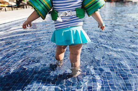 punta cana - Young girl walking in shallow water in outdoor swimming pool, rear view, low section Stock Photo - Premium Royalty-Free, Code: 614-09038637