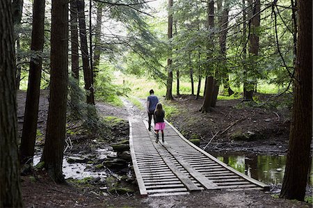 simsearch:614-09038795,k - Two girls walking across wooden footbridge in forest, rear view Fotografie stock - Premium Royalty-Free, Codice: 614-09038771