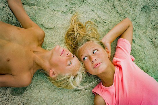 Overhead portrait of blond brother and sister lying opposite each other on beach Foto de stock - Sin royalties Premium, Código de la imagen: 614-09038818