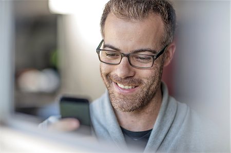 people looking at smartphone home not children - Happy businessman looking at smartphone at home Stock Photo - Premium Royalty-Free, Code: 614-09038957