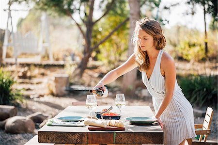 santa barbara - Young woman, outdoors, preparing dinner table, pouring wine Photographie de stock - Premium Libres de Droits, Code: 614-09056604