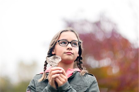 simsearch:614-09056681,k - Portrait of girl with plaits and glasses holding leaf Fotografie stock - Premium Royalty-Free, Codice: 614-09056682