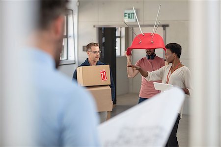 Colleagues in office carrying cardboard boxes and chair Stock Photo - Premium Royalty-Free, Code: 614-09056714