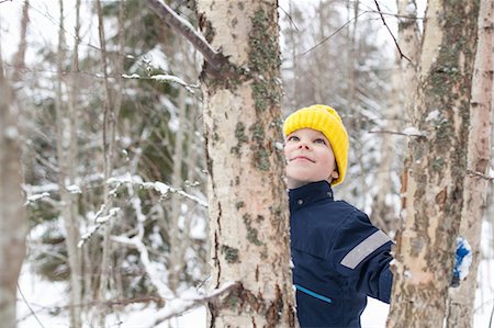 simsearch:614-09212275,k - Boy in yellow knit hat looking up at tree in snow covered forest Photographie de stock - Premium Libres de Droits, Code: 614-09056756