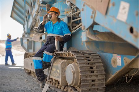 simsearch:614-09056785,k - Quarry worker resting on heavy machinery, drinking from flask cup Photographie de stock - Premium Libres de Droits, Code: 614-09056792