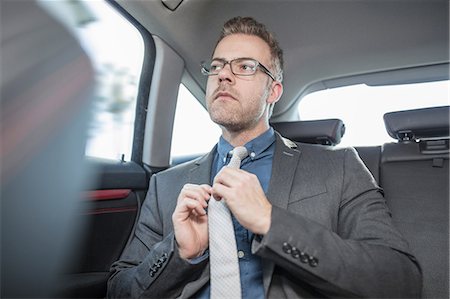 raddrizzare - Businessman sitting in back of car, straightening tie Fotografie stock - Premium Royalty-Free, Codice: 614-09056804