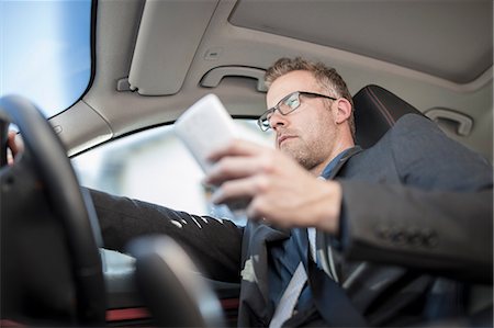 simsearch:614-07652557,k - Businessman driving car, holding smartphone, low angle view Stock Photo - Premium Royalty-Free, Code: 614-09056809
