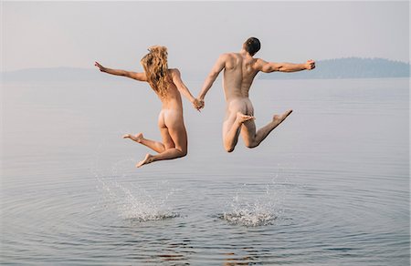 Rear view of nude couple in water jumping in mid air Stock Photo - Premium Royalty-Free, Code: 614-09056879