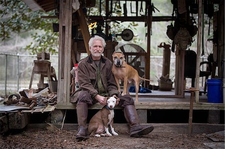 simsearch:649-07437708,k - Man with pet dogs by wooden work hut Photographie de stock - Premium Libres de Droits, Code: 614-09056928