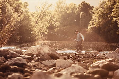Fisherman ankle deep in sunlit river, Mozirje, Brezovica, Slovenia Stock Photo - Premium Royalty-Free, Code: 614-09057013