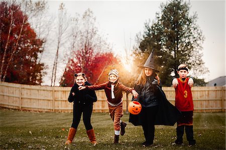 Portrait of boy and girls posed in halloween costumes in garden at sunset Stock Photo - Premium Royalty-Free, Code: 614-09057085