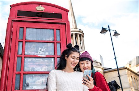 Two young stylish women looking at smartphone by red phone box, London, UK Foto de stock - Sin royalties Premium, Código: 614-09057109