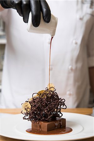 Chef pouring cream over chocolate nest cake decoration on cake Stock Photo - Premium Royalty-Free, Code: 614-09057192