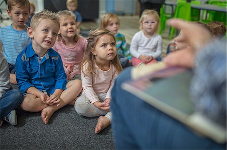 Young children sitting on carpet in classroom, listening to teacher at front of class Stock Photo - Premium Royalty-Free, Code: 614-09057214