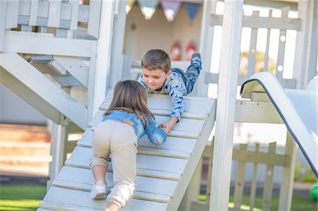 Girl and boy at preschool, helping hand to crawl up ramp on climbing frame in garden Foto de stock - Sin royalties Premium, Código: 614-09057255
