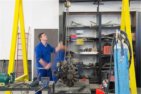 Male car mechanic hoisting car engine in repair garage Stock Photo - Premium Royalty-Free, Code: 614-09057383