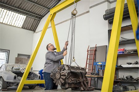 Male car mechanic hoisting car engine in repair garage Stock Photo - Premium Royalty-Free, Code: 614-09057399