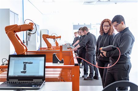 robot - Robotics apprentices using test industrial robots in robotics facility Photographie de stock - Premium Libres de Droits, Code: 614-09057427