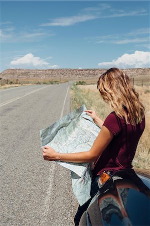 Woman leaning against car looking at map Stock Photo - Premium Royalty-Free, Code: 614-09078736