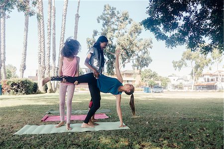 Girls and teenage schoolgirls practicing yoga standing half moon pose on school playing field Stock Photo - Premium Royalty-Free, Code: 614-09078935