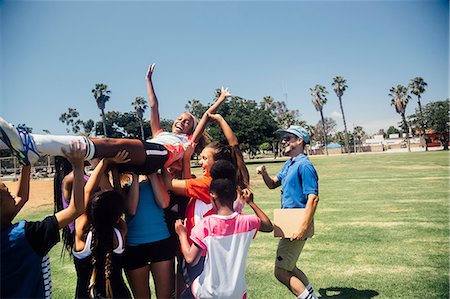 Schoolgirl soccer team carrying player above their heads on school sports field Stock Photo - Premium Royalty-Free, Code: 614-09078969