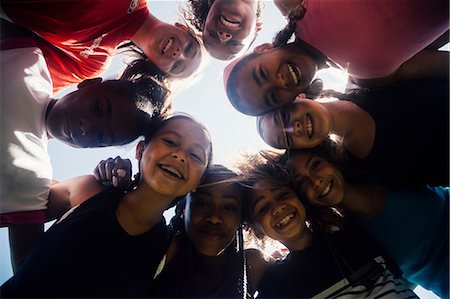 Low angle view of schoolgirl soccer team huddled in circle Stock Photo - Premium Royalty-Free, Code: 614-09078971