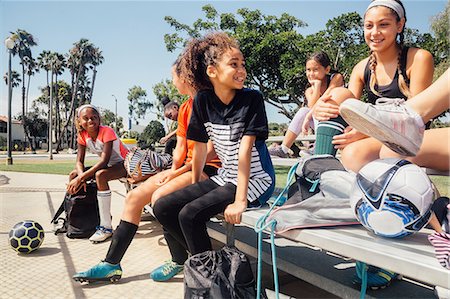 Schoolgirl soccer players chatting on school sports field bench Photographie de stock - Premium Libres de Droits, Code: 614-09079018