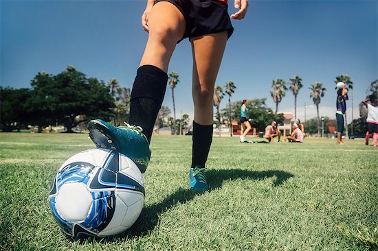 Waist down of teenage schoolgirl soccer player with foot on ball on school sports field Photographie de stock - Premium Libres de Droits, Le code de l’image : 614-09079062