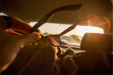 enroute - Young man wiping sunglasses inside sunlit car, close up Stock Photo - Premium Royalty-Free, Code: 614-09079147