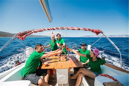Men and young women on board yacht raising a toast with sliced water melon, Croatia Foto de stock - Sin royalties Premium, Código: 614-09110709