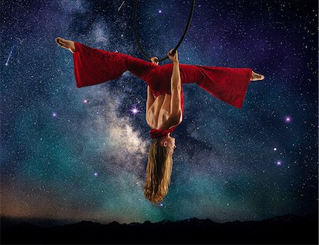 red on red - Young female aerial acrobat doing splits hanging upside down from hoop, milky way background Stock Photo - Premium Royalty-Free, Code: 614-09110718