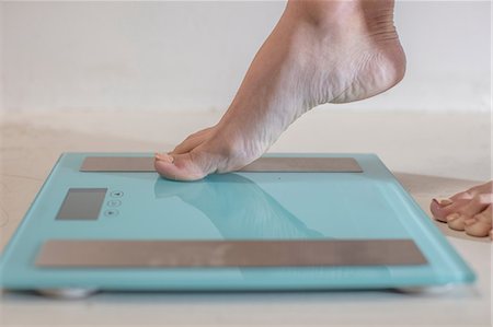 feet in the bathroom - Young woman stepping onto weighing scales, close up of foot Stock Photo - Premium Royalty-Free, Code: 614-09110958