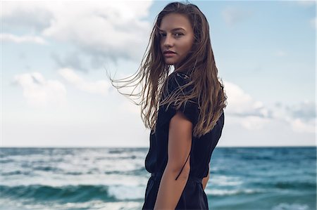 Portrait of young woman looking over her shoulder on beach, Odessa, Odessa Oblast, Ukraine Foto de stock - Royalty Free Premium, Número: 614-09110986