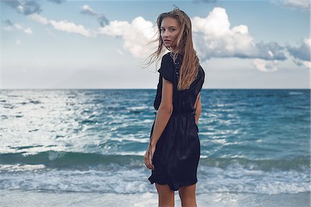 Portrait of young woman looking over her shoulder on beach, Odessa, Odessa Oblast, Ukraine Stock Photo - Premium Royalty-Free, Code: 614-09110987