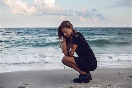 Young woman crouching by water's edge on beach, Odessa, Odessa Oblast, Ukraine Foto de stock - Sin royalties Premium, Código: 614-09110983