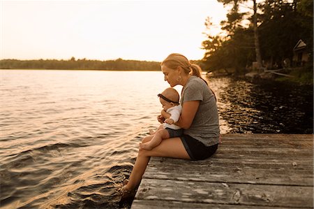 simsearch:649-08084693,k - Mother sitting on pier with baby daughter looking down at  lake Foto de stock - Royalty Free Premium, Número: 614-09111017