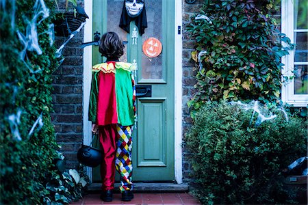 Young boy in halloween costume, standing at door, trick or treating, rear view Stock Photo - Premium Royalty-Free, Code: 614-09127261