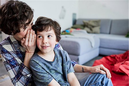 Mother and son at home, mother whispering into son's ear Stock Photo - Premium Royalty-Free, Code: 614-09127321
