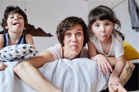 simsearch:614-09127392,k - Portrait of mother, son and daughter, lying on bed, poking tongue out Stock Photo - Premium Royalty-Free, Code: 614-09127354