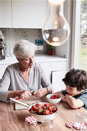 simsearch:614-09127363,k - Grandmother sitting at kitchen table, preparing strawberries, grandson sitting beside her, watching Stock Photo - Premium Royalty-Free, Code: 614-09127397