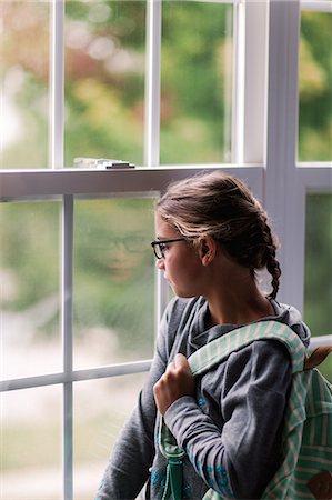 Girl with backpack gazing through house window Stock Photo - Premium Royalty-Free, Code: 614-09127471