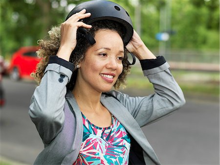 simsearch:614-06536783,k - Mid adult woman putting on bicycle safety helmet Fotografie stock - Premium Royalty-Free, Codice: 614-09135020