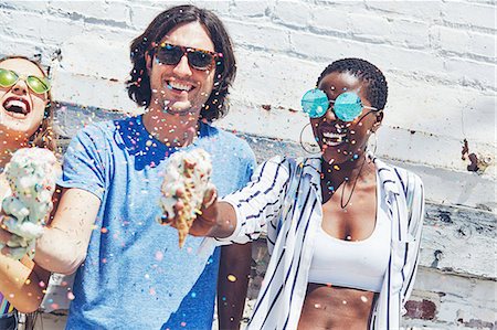 Young man and women holding melting ice cream cones, showering in sugar strands Stockbilder - Premium RF Lizenzfrei, Bildnummer: 614-09147717