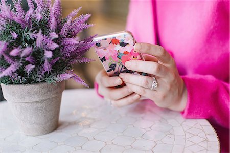 pink - Young woman sitting at table using smartphone,  close up Stock Photo - Premium Royalty-Free, Code: 614-09147749