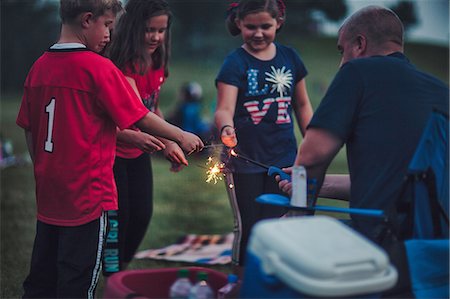 Father lighting sparklers for group of children Stock Photo - Premium Royalty-Free, Code: 614-09147769