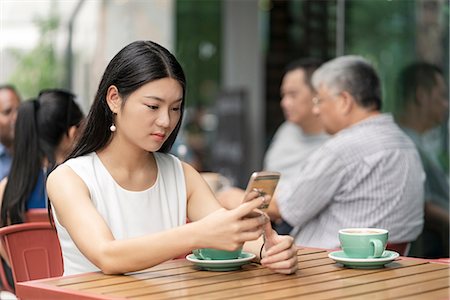 simsearch:649-08145347,k - Businesswoman sitting outdoors, at cafe, using smartphone Stock Photo - Premium Royalty-Free, Code: 614-09156727