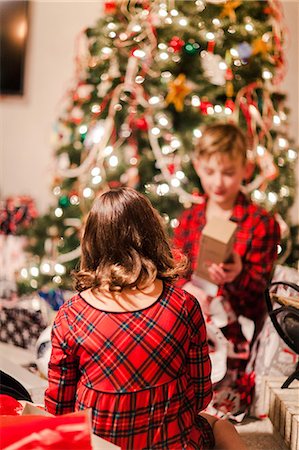 simsearch:649-08969030,k - Siblings opening Christmas gifts by Christmas tree Photographie de stock - Premium Libres de Droits, Code: 614-09159651