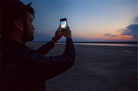 simsearch:649-09148811,k - Man in hat taking photograph of sunset on beach, Odessa, Ukraine Stock Photo - Premium Royalty-Free, Code: 614-09168193