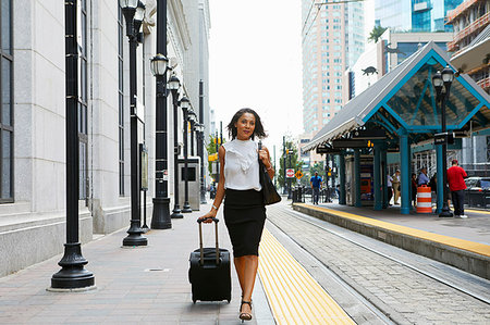 simsearch:614-09178279,k - Businesswoman pulling luggage alongside train Foto de stock - Sin royalties Premium, Código: 614-09178222