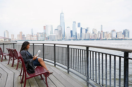 Businesswoman reading newspapers, New York City skyline in background Stock Photo - Premium Royalty-Free, Code: 614-09178301